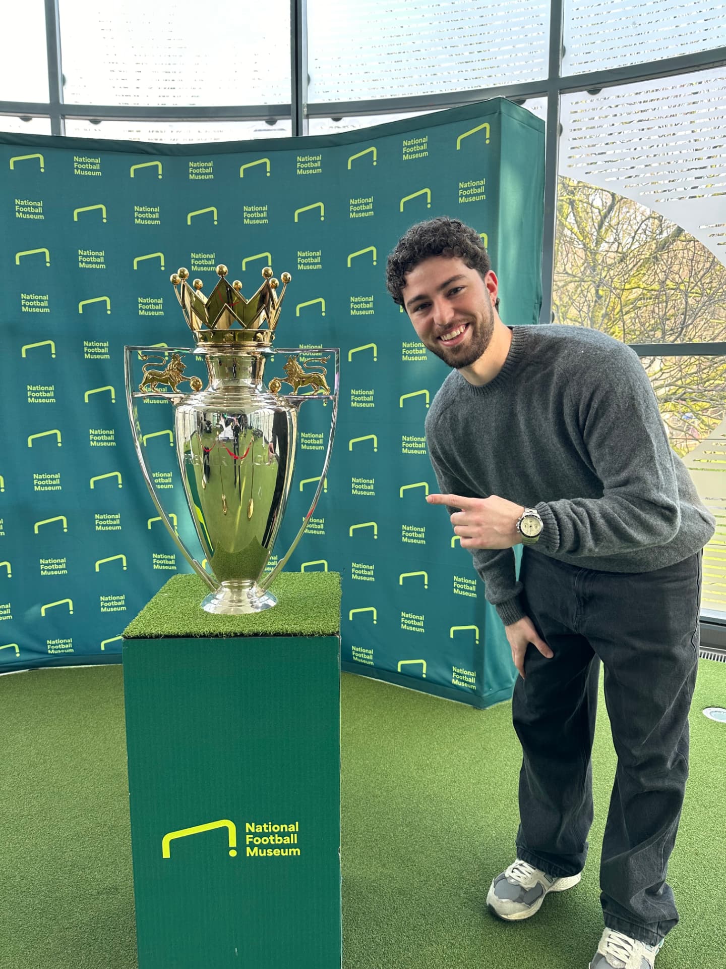 Silver football trophy under a spotlight inside a stadium